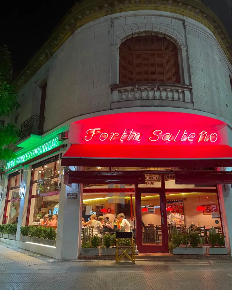 Esquina de Fortín Salteño en Av. Cabildo de noche, con su cartel de neón rojo y el salón lleno de clientes